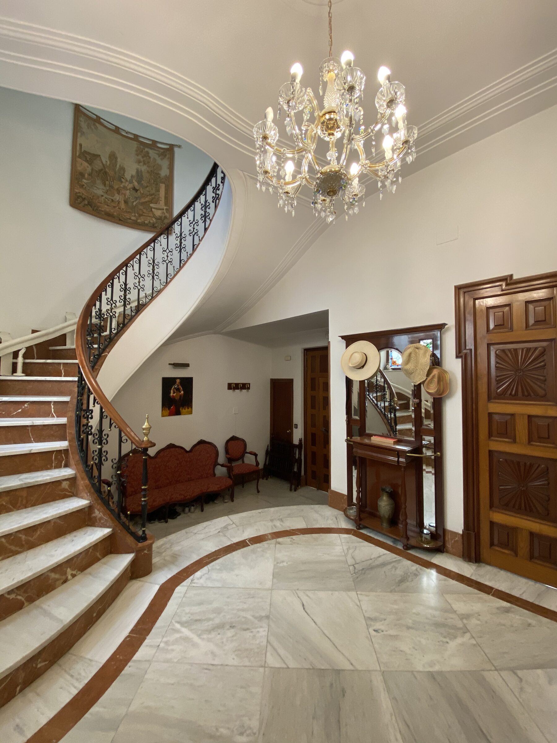 The entrance hall side of the staircase, with a console table and the chandelier above.